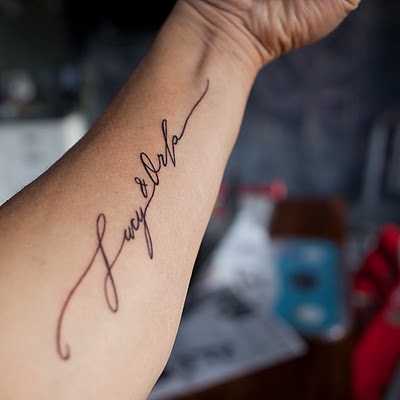 Girl Lights Poxleitner With Cursive Tattoo Lettering On Her Arms